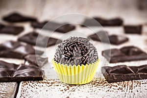 Brigadeiro or negrinho, a chocolate candy typical of Brazil. On white wooden table with pieces of chocolate around photo