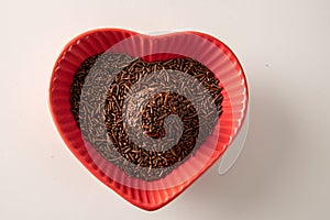 Brigadeiro over a red heart shaped bowl i isolated on white background photo