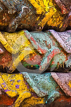 Bright abstract background of multicolored old painted tractor tires. Yellow, red, purple, turquoise paint. Cracked rubber texture