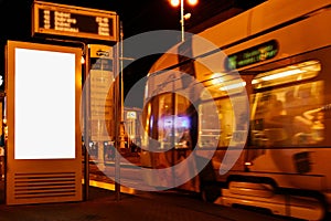 Night scene at tram stop with blank advertising panel