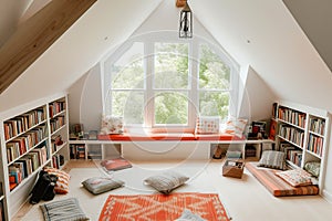 bright attic room with floor cushions, bookshelves, and a window seat