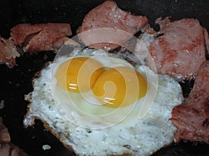 Bright attractive delicious fresh double yolk sunny side up with luncheon meat close up