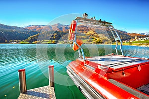 Bright autumn view of San Valentino village and Muta lake Haidersee and resque boat photo