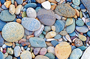 Bright background of multi-colored round stones, sea pebbles, close up.