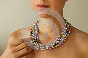 Bright beads of Murano glass on a young girl. The girl`s hand touches the beads