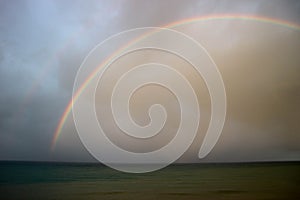 Bright beautiful colorful full arc rainbow over the sea