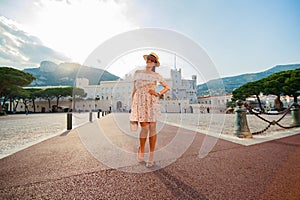 a bright beautiful girl in a light dress and hat walks along the streets of old town of Monaco in sunny weather, a