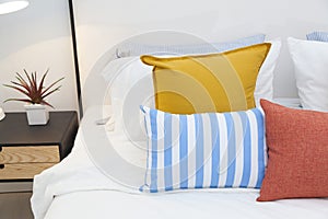 Bright bedroom interior with striped pillow on bed and bedside table lamp