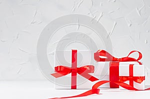 Bright birthday background - white gift boxes with red bow, curl ribbon in white light interior, copy space.