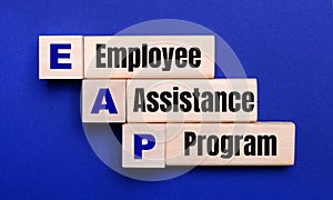 On a bright blue background, light wooden blocks and cubes with the text EAP Employee Assistance Program