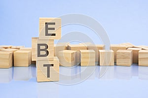 on a bright blue background, light wooden blocks and cubes with the text EBT