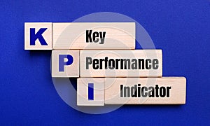 On a bright blue background, light wooden blocks and cubes with the text KPI Key Performance Indicator