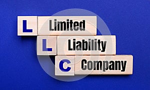 On a bright blue background, light wooden blocks and cubes with the text LLC Limited Liability Company