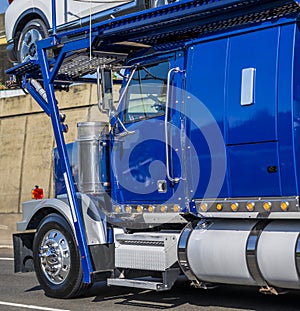 Bright blue big rig car hauler semi truck transporting cars driving on the road