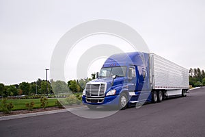 Bright blue big rig semi truck with reefer running on the road