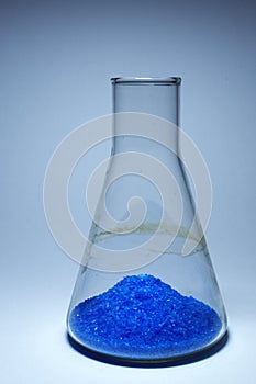 Bright blue crystals in a heap, on bottom of Erlenmeyer flask