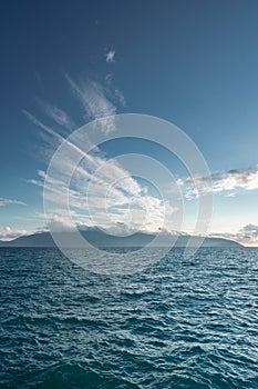 Bright blue ocean in a cloudy blue sky, with islands on the horizon in albania