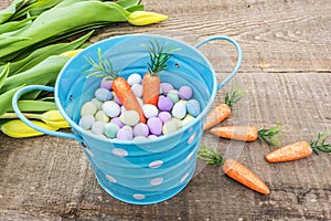 Bright blue pastel bucket filled with candy eggs and carrots, si