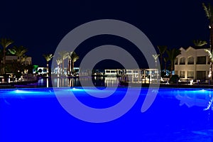 Bright blue pool by the sea in the hotel at night