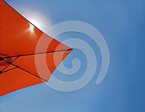 Bright blue sky background with a red beach umbrella. Theme of tourism, relax, vacation, holiday, repose, take a rest by the sea.