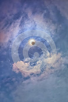 Bright blue sky with clouds and a solar eclipse