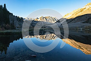 Bright blue still lake surface reflectiong surrounding mountain photo