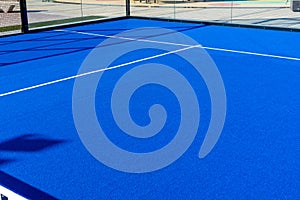 Bright blue tennis, paddle ball or pickleball court view from net to service boxes and base line outdoors