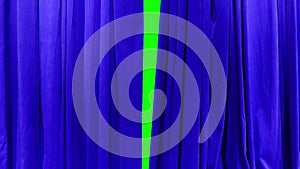 A bright blue theatrical curtain moves apart in different directions behind a green background