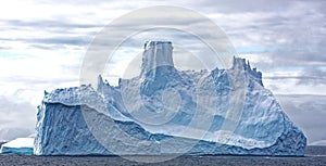 Bright blue and turquoise iceberg in grey southpolar ocean