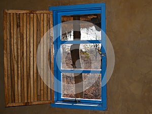 Bright blue window with open slat slat wooeden shutter and view photo