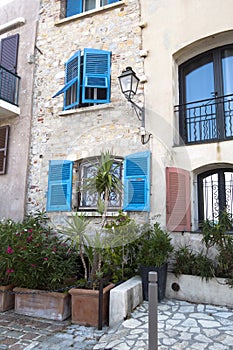 Bright blue window shutters and potted flowers on the old paved