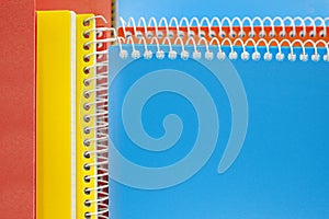 Bright blue, yellow and orange notebooks on a spring, and business background