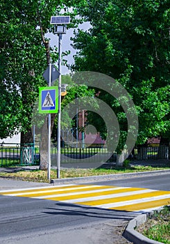 Bright blue and yellow pedestrian crosswalk sign on a town street with traffic warning.