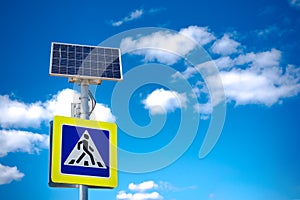 Bright blue and yellow pedestrian crosswalk sign with traffic warning. Powered by solar energy with its own solar panel