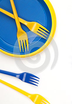 Bright blue and yellow plastic disposable tableware on white background close-up