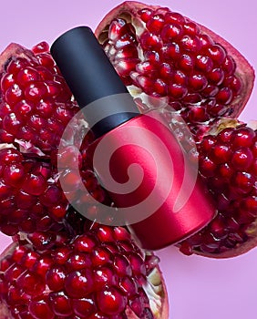Bright bottle of nail polish on a blue background with pomegranate fruits