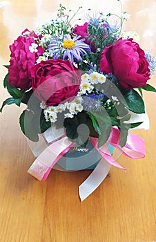 A bright bouquet of pink roses, white and blue chamomile, white gypsophila, green mint in a box of light green, created by a flori