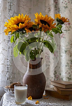 A bright bouquet of sunflowers in a vintage clay jug on a lace tablecloth by the curtained window