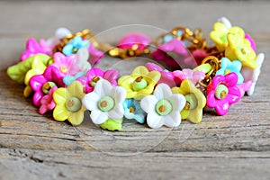 Bright bracelet isolated on old wooden background. Bracelet made of colorful plastic flowers, leaves and beads. Accessory