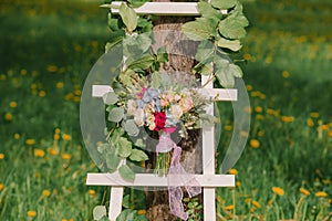 Bright bride`s bouquet on a white stepladder on a green grass