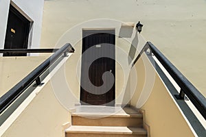 Bright building with a dark door. Staircase to the hotel room. Doors in the hotel room.