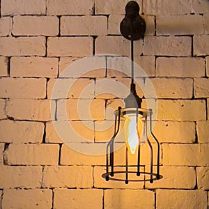 bright caged steel lamp shining on a brick wall