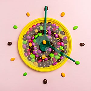 Bright candies dragees on a yellow plate with green spoons