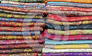 Bright cashmere shawls in the bazaar. Background with oriental shawls