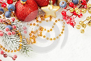 Bright Christmas composition with red baubles, holly berries, Xmas tree branch and golden garland on white snow background