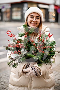 bright Christmas flower arrangement in pot of spruce branches and red berries and eucalyptus in female hands