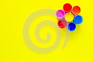 A bright circle similar to a flower made up of cans of paint on a yellow background with a place for text. top view
