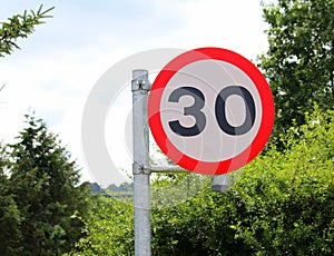 Bright, clean, new, speed limit sign British 30mph in country setting.