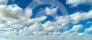 Bright clear blue sky and contrasting white cumulous puffy clouds distance perspective