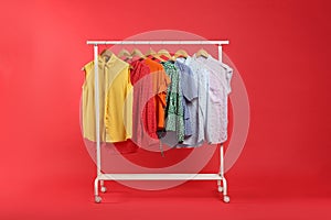 Bright clothes hanging on rack against background. Rainbow colors